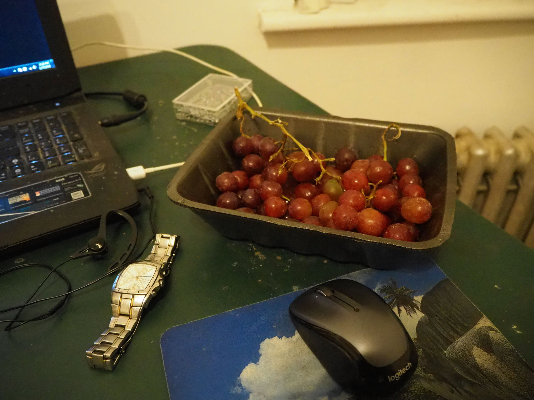 the grapes sitting on a green table in an apartment with a laptop and mouse